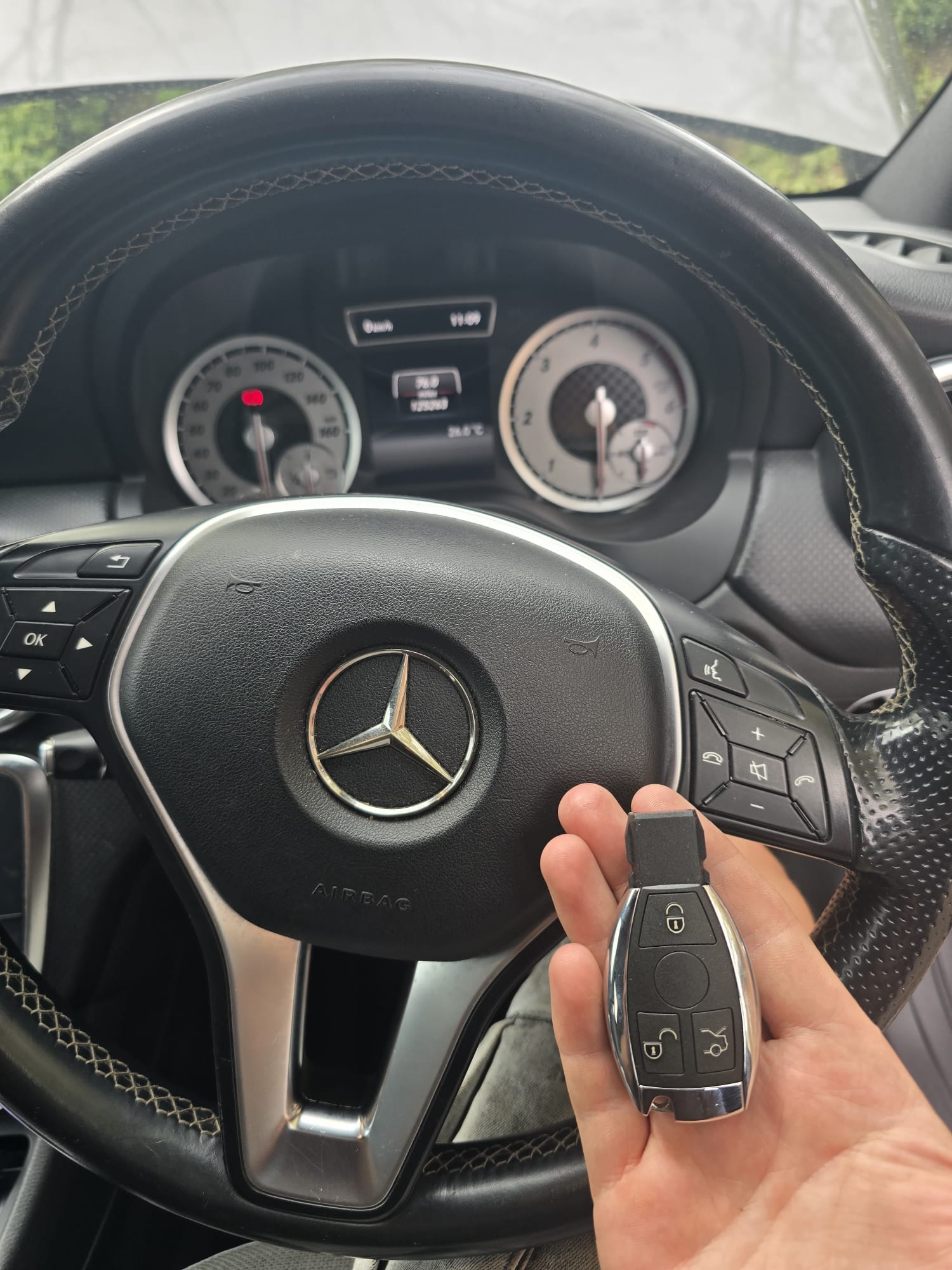 Mercedes A-Class chrome smart key held in front of the steering wheel after programming