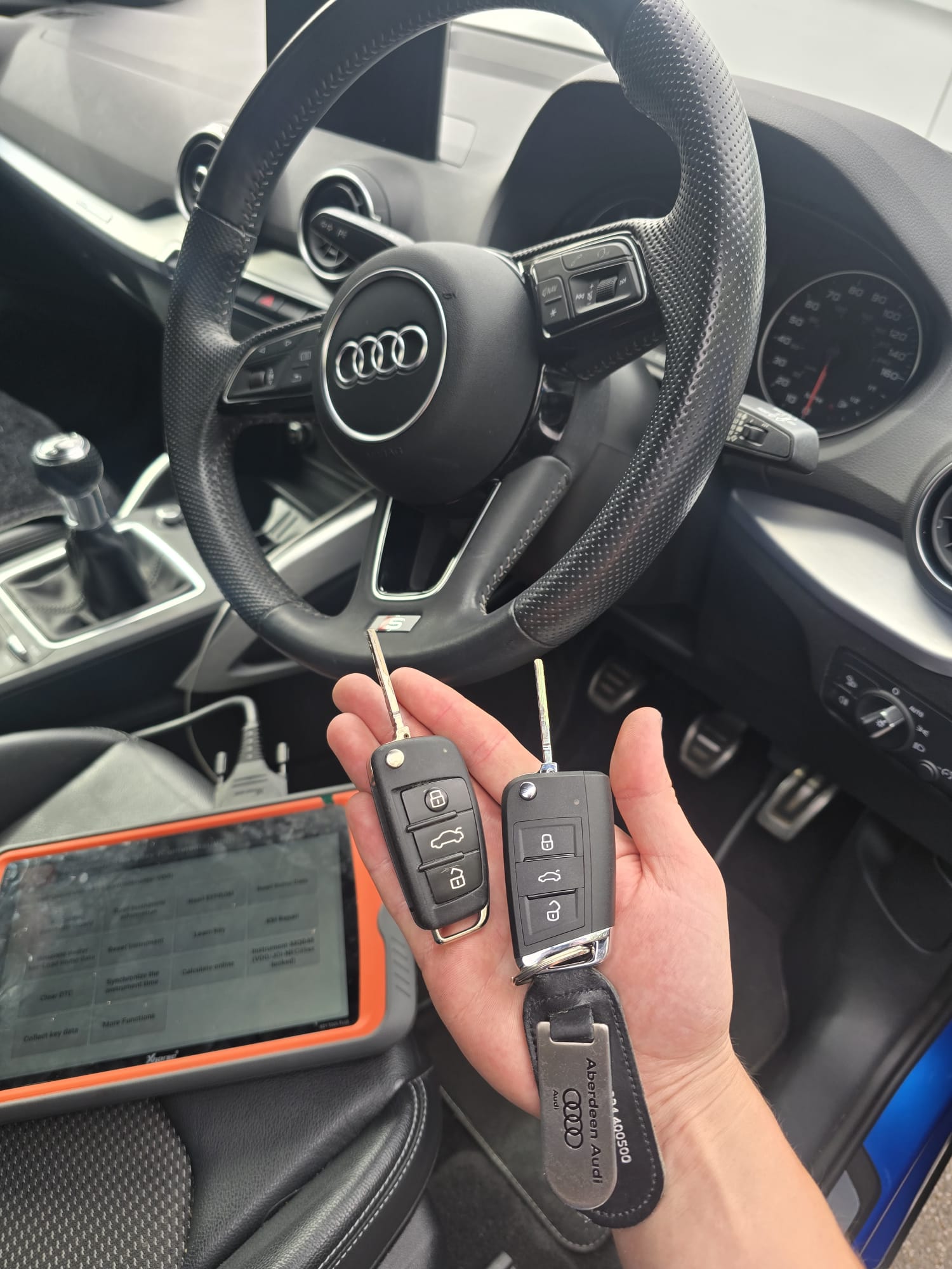 Audi replacement car key cut and programmed beside the steering wheel using professional diagnostic equipment