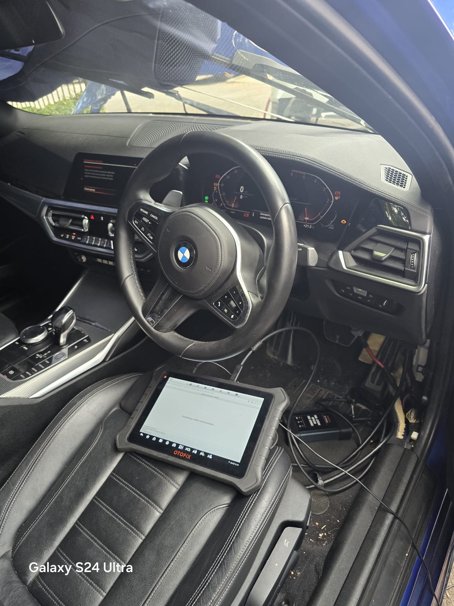 OtoFix diagnostic tablet connected inside a BMW establishing vehicle communication for key programming