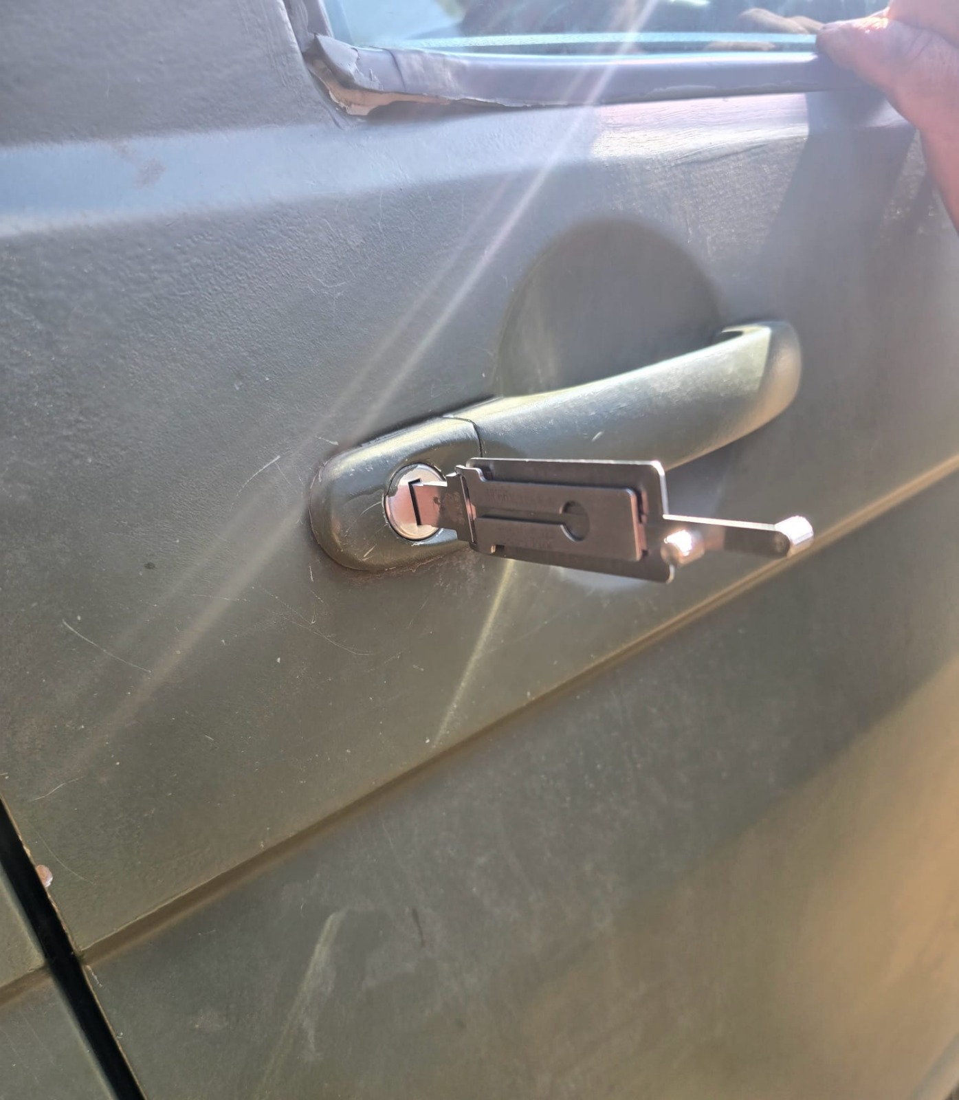 Non-destructive lock pick unlocking a grey car door — zero damage to the paintwork or lock