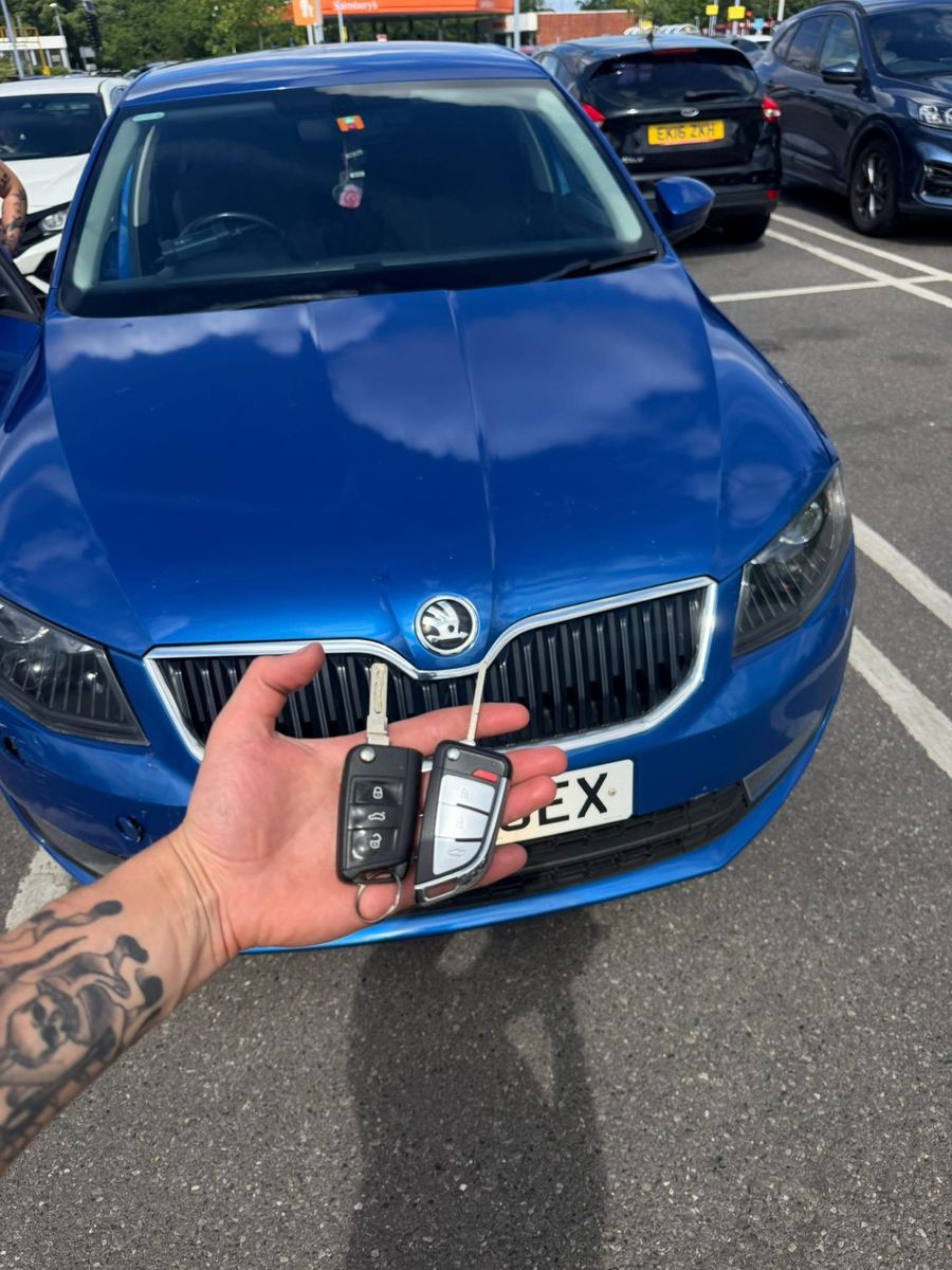 Two Skoda keys cut and programmed in front of a blue Skoda Octavia in West London